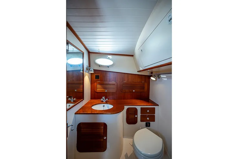 Slide: The Image of Hinckley Picnic Boat 37 MKIII 2016 bathroom with wooden cabinetry and round porthole window. - 19