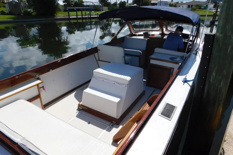Slide: The Image of 1995 Lyman 27 Cruisette boat docked, featuring spacious seating and canopy. - 12