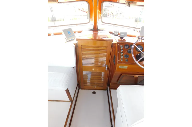 Slide: The Image of Interior of a 1995 Lyman 27 Cruisette boat with wooden dashboard and white seating. - 17