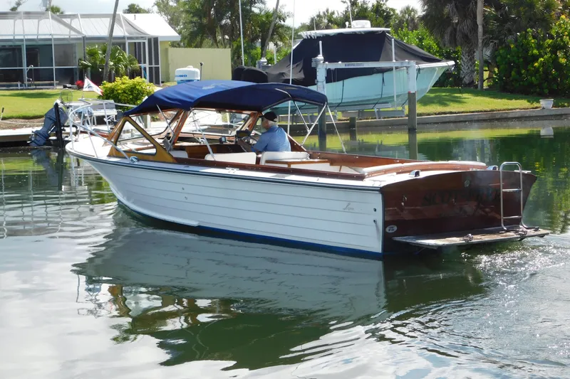Slide: The Image of 1995 Lyman 27 Cruisette boat with blue canopy on calm water near dock. - 2