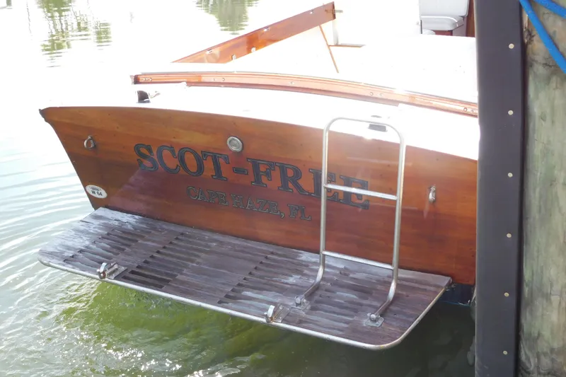 Slide: The Image of 1995 Lyman 27 Cruisette boat docked, featuring wooden stern and swim platform. - 24