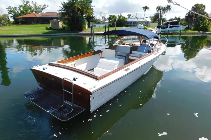 Slide: The Image of 1995 Lyman 27 Cruisette boat with blue canopy on calm water near lush greenery. - 3