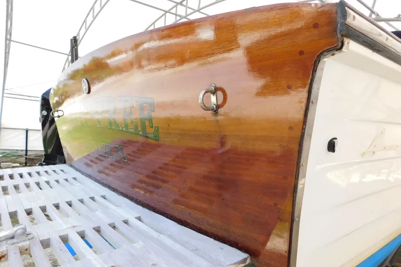 Slide: The Image of The image shows the polished wooden stern of a 1995 Lyman 27 Cruisette. - 38