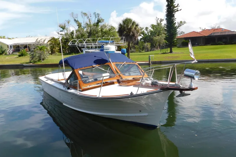 Slide: The Image of 1995 Lyman 27 Cruisette boat docked on a calm waterway. - 4