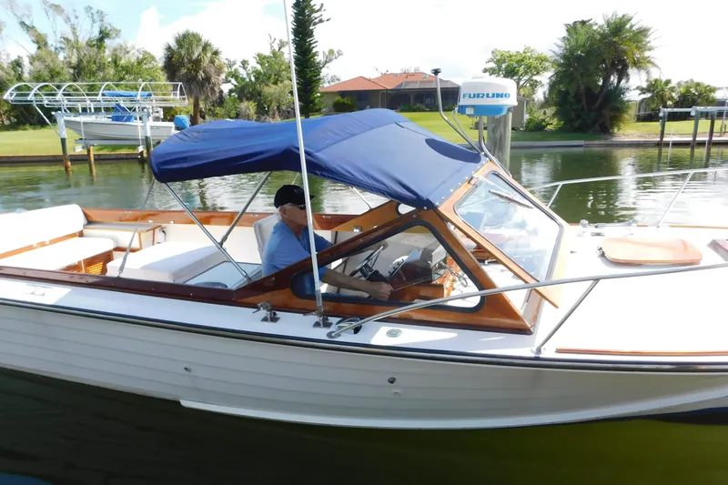 Slide: The Image of 1995 Lyman 27 Cruisette boat with blue canopy on a calm waterway. - 7