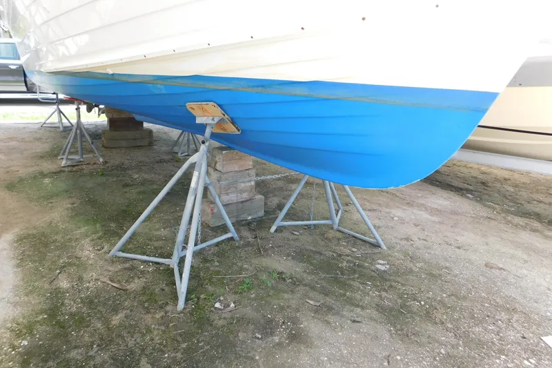 Slide: The Image of 1995 Lyman 27 Cruisette boat hull on stands, blue and white exterior. - 36
