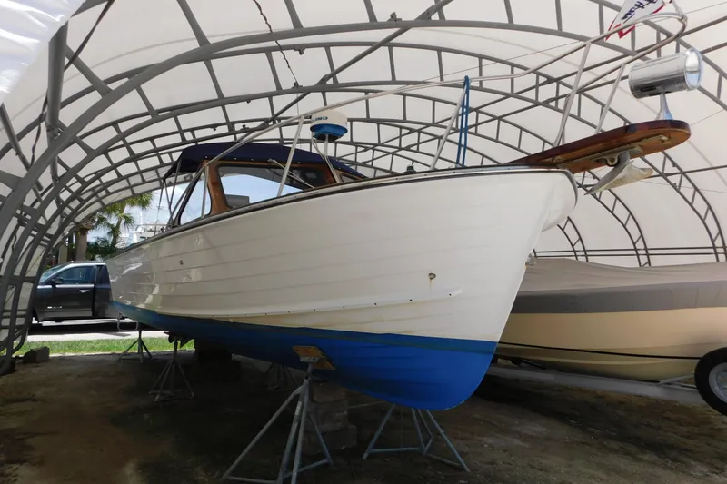 Slide: The Image of 1995 Lyman 27 Cruisette boat under a protective canopy, displayed on stands. - 1