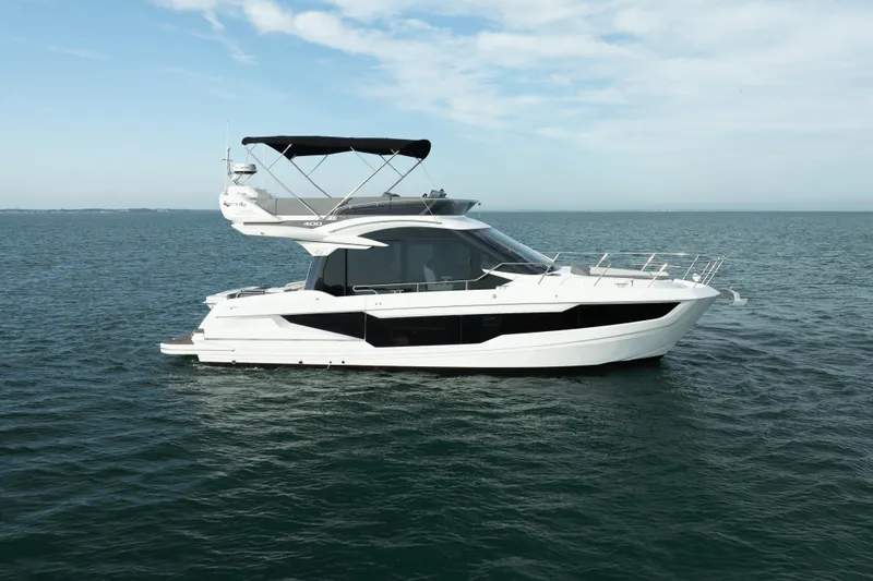 Slide: The Image of 2023 Galeon 400 Fly yacht cruising on open water under a clear sky. - 1