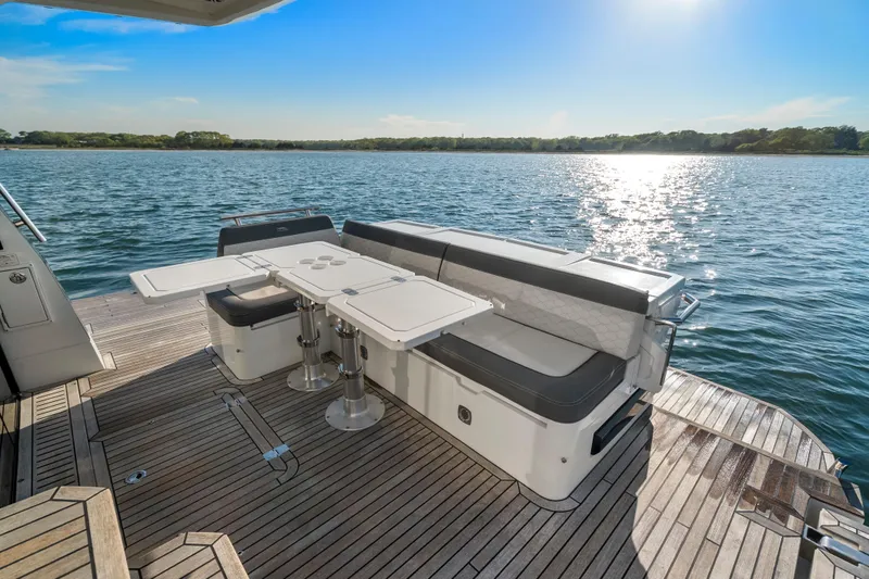 Slide: The Image of 2023 Galeon 400 Fly yacht deck with seating and table, overlooking serene water. - 13