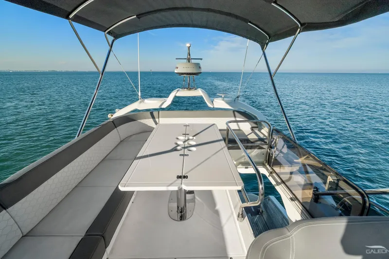 Slide: The Image of 2023 Galeon 400 Fly yacht flybridge with seating and table, overlooking serene ocean waters. - 40