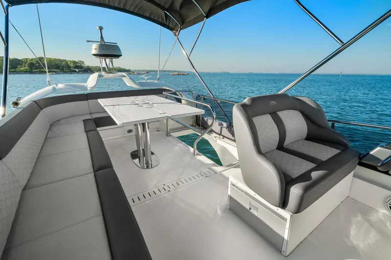 Slide: The Image of 2023 Galeon 400 Fly yacht flybridge with seating and table, overlooking serene ocean view. - 42