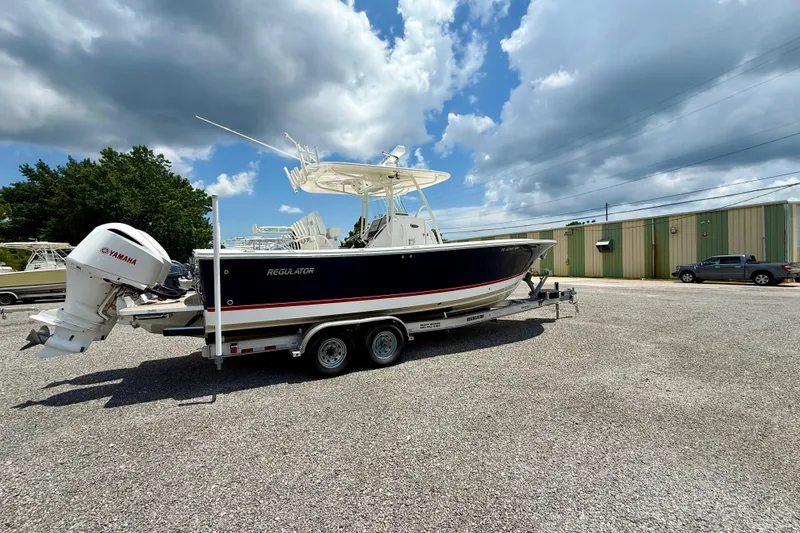 Slide: The Image of 2017 Regulator 28 boat on trailer with Yamaha outboard, parked outdoors under cloudy sky. - 1