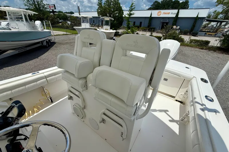 Slide: The Image of 2017 Regulator 28 boat with white cushioned seating and steering wheel, parked outdoors. - 5