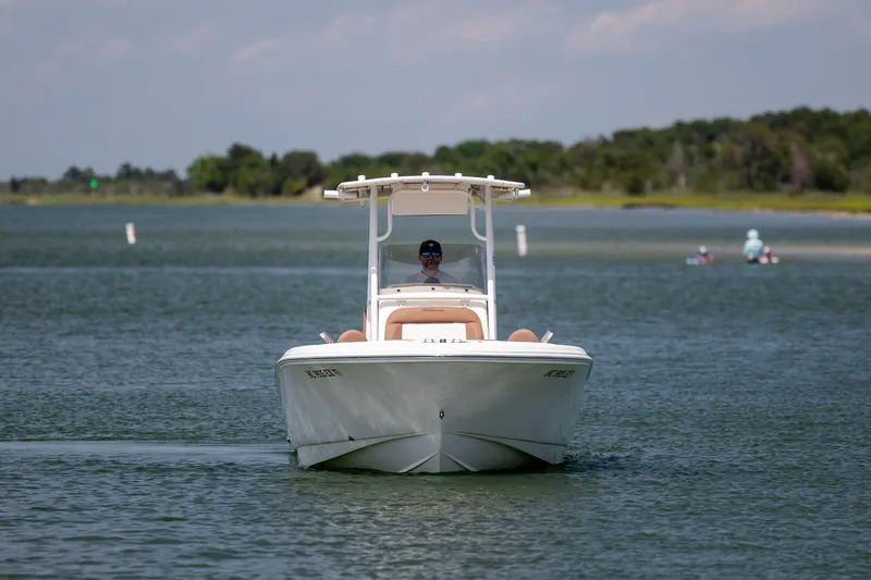 Slide: The Image of 2022 Pioneer 202 Islander boat cruising on a calm lake with scenic background. - 10