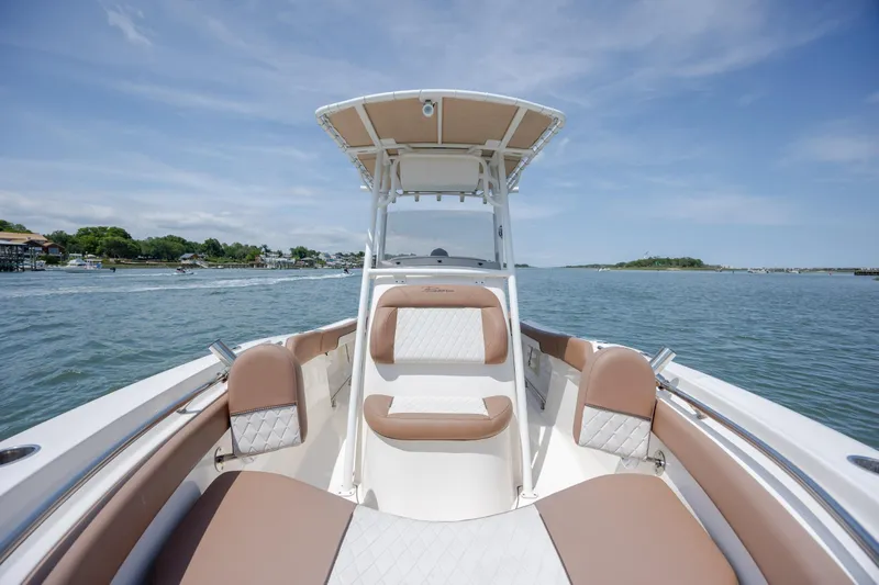 Slide: The Image of 2022 Pioneer 202 Islander boat interior with cushioned seating on a sunny day. - 13
