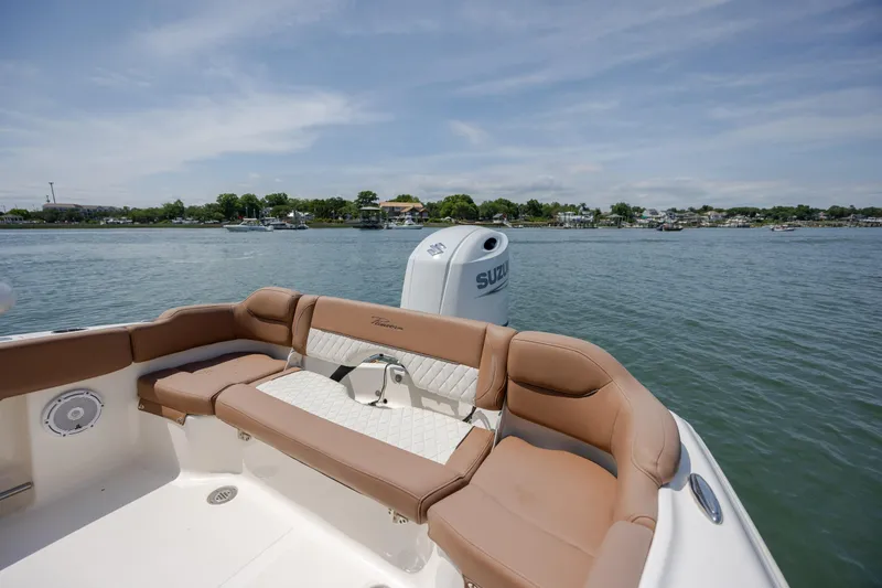 Slide: The Image of 2022 Pioneer 202 Islander boat with tan seating, on calm water, scenic shoreline view. - 20