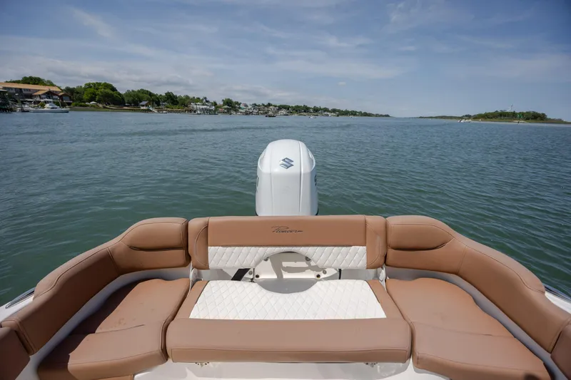Slide: The Image of 2022 Pioneer 202 Islander boat with tan seating, on a calm lake under a clear sky. - 21