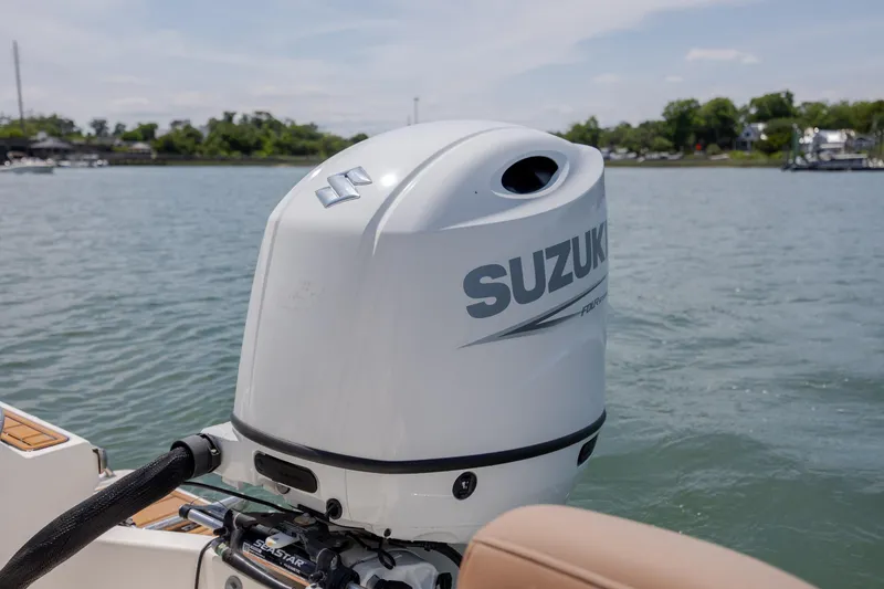 Slide: The Image of Outboard motor on 2022 Pioneer 202 Islander boat, Suzuki branding, on calm water. - 24