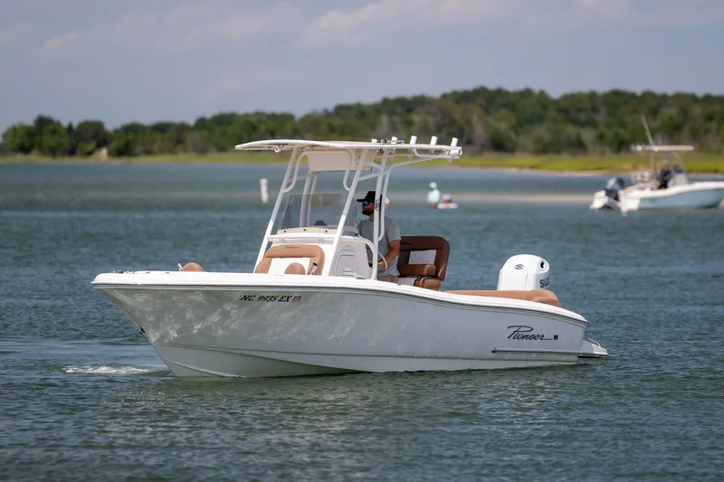 Slide: The Image of 2022 Pioneer 202 Islander boat cruising on a calm lake with scenic background. - 9