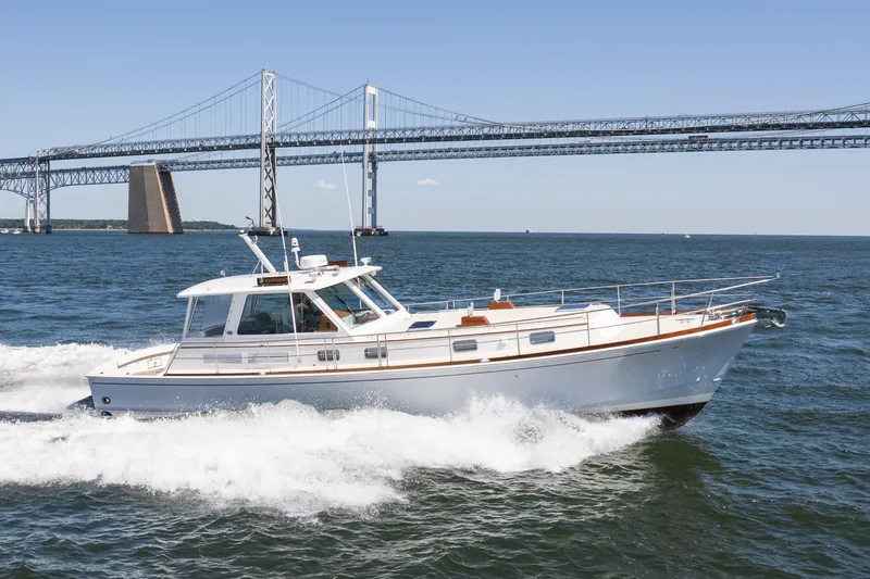 The Image of 1999 Grand Banks 49 Eastbay HX cruising near a large bridge on a sunny day. - 1