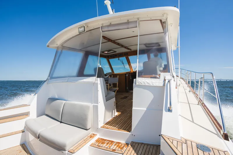 Slide: The Image of 1999 Grand Banks 49 Eastbay HX cruising on open water, showcasing deck and seating area. - 14