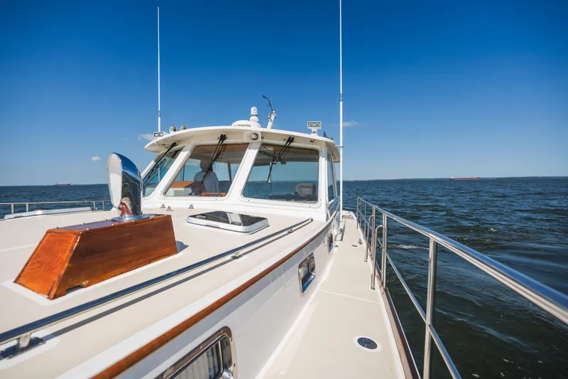 Slide: The Image of 1999 Grand Banks 49 Eastbay HX cruising on open water under clear blue skies. - 18