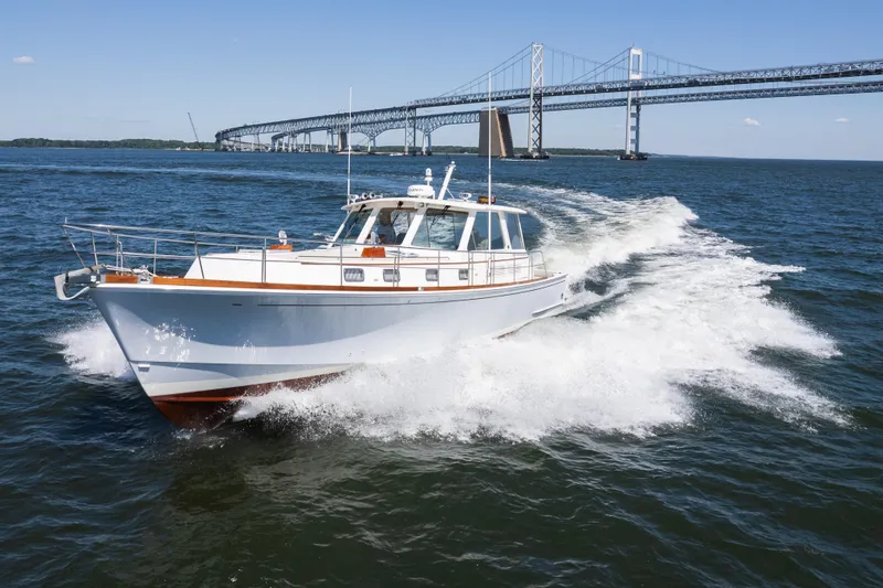 Slide: The Image of 1999 Grand Banks 49 Eastbay HX cruising near a large bridge on open water. - 2