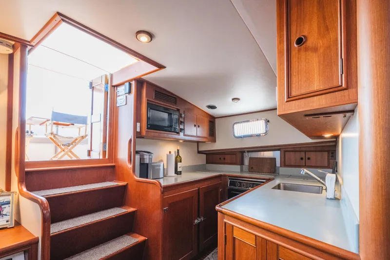 Slide: The Image of Luxurious 1999 Grand Banks 49 Eastbay HX yacht interior with wooden cabinetry and modern kitchen amenities. - 44