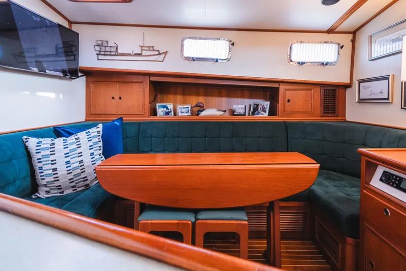 Slide: The Image of Cozy interior of 1999 Grand Banks 49 Eastbay HX with wooden table and green seating. - 47