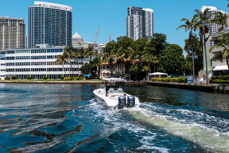 Slide: The Image of Everglades 295 Center Console boat cruising near urban waterfront, 2021 model. - 1