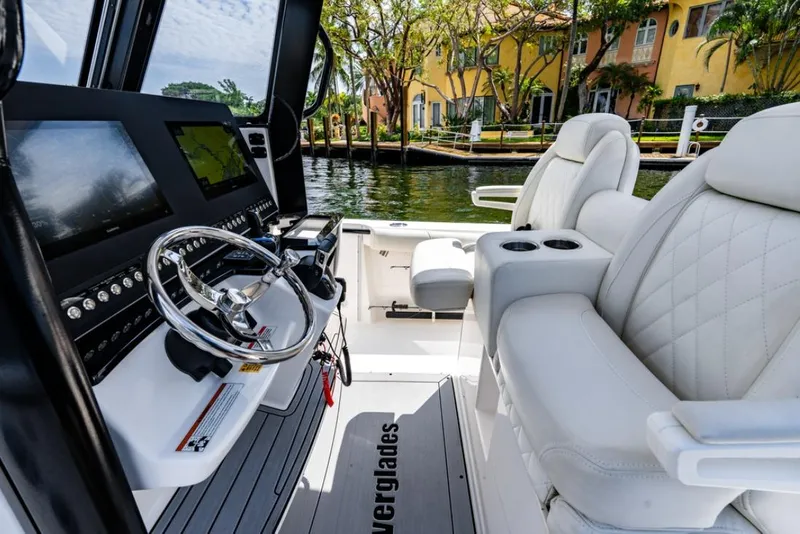 Slide: The Image of 2021 Everglades 295 Center Console boat with luxurious seating, docked near waterfront homes. - 10