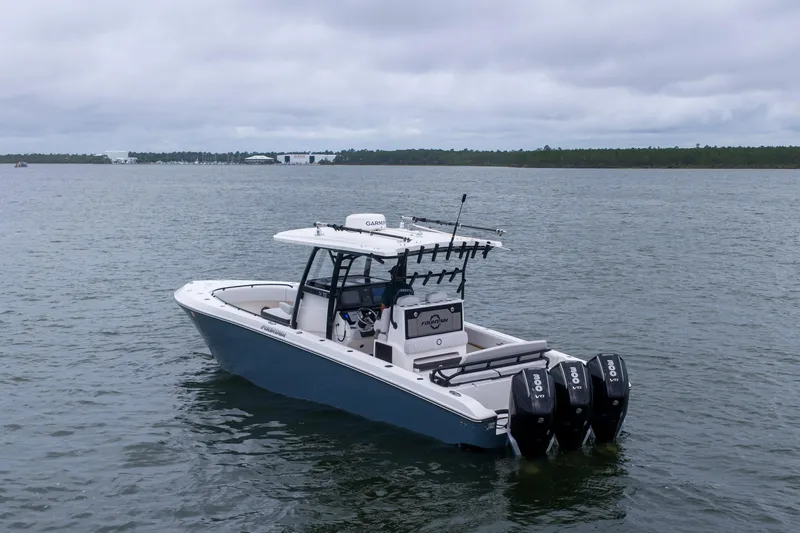 Slide: The Image of 2024 Fountain Bluewater 34 Tournament Edition boat on calm water, featuring triple outboard engines. - 28
