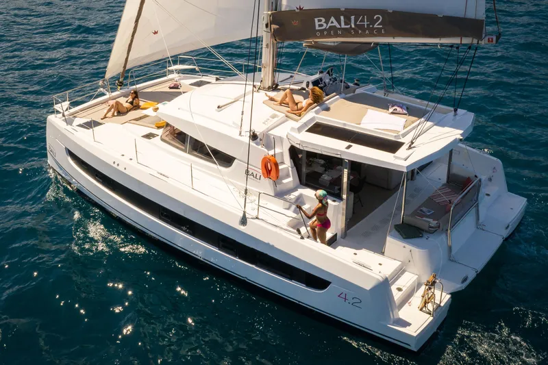 Slide: The Image of 2026 Bali 4.2 catamaran sailing on open sea with passengers relaxing on deck. - 1