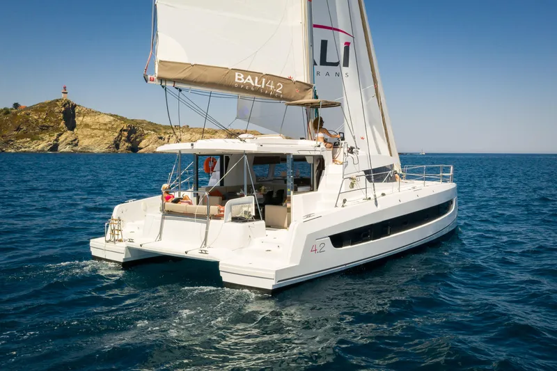 Slide: The Image of 2026 Bali 4.2 catamaran sailing on clear blue waters near a rocky coastline. - 45