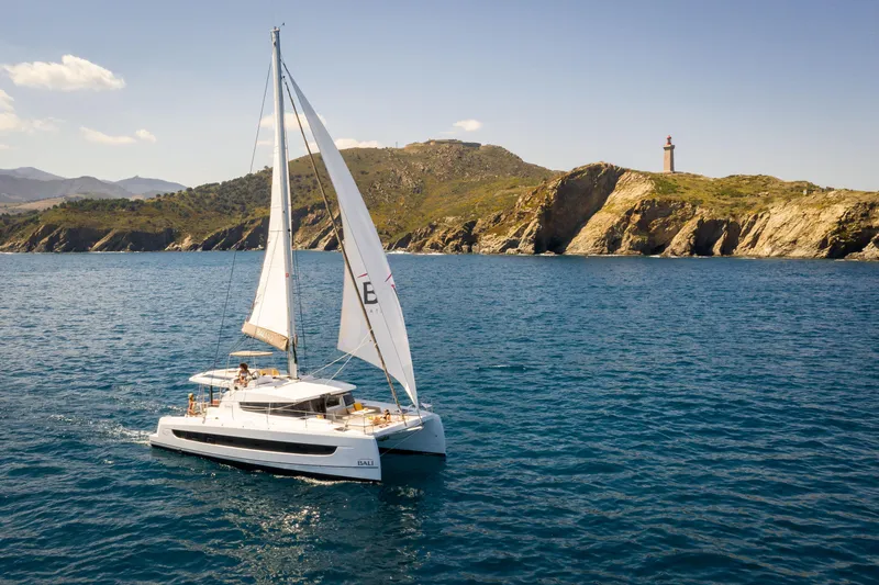 Slide: The Image of Sailing catamaran Bali 4.2 (2026) on blue sea near rocky coastline and lighthouse. - 47