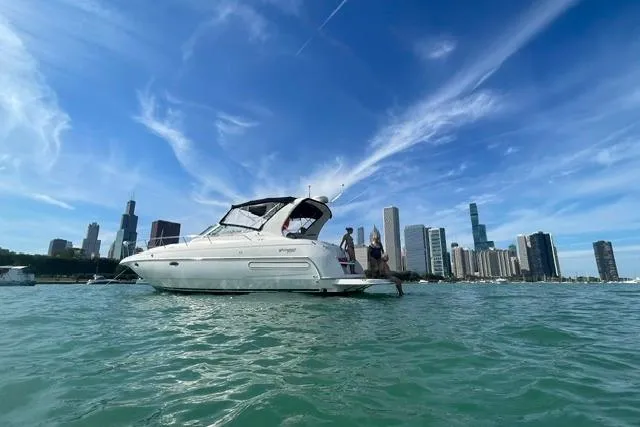 The Image of 2000 Cruisers Yachts 3575 Express on water with city skyline backdrop. - 0