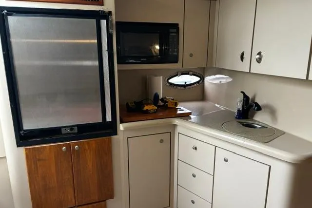 Slide: The Image of Kitchen area of 2000 Cruisers Yachts 3575 Express with microwave and compact fridge. - 5