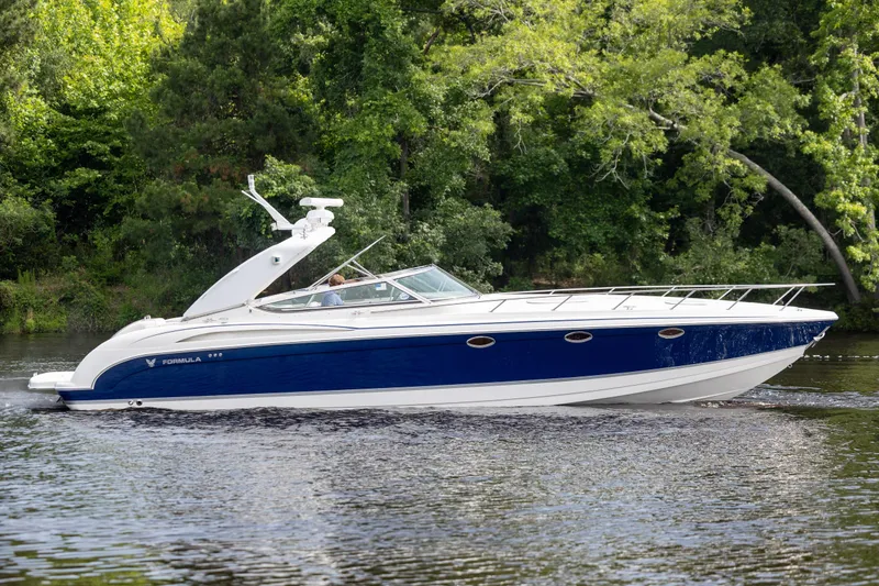 Slide: The Image of 2003 Formula 400 Super Sport boat cruising on a serene river with lush green trees. - 1