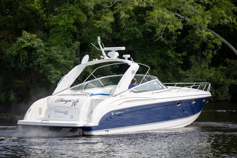 Slide: The Image of 2003 Formula 400 Super Sport boat cruising on a serene river with lush greenery. - 2