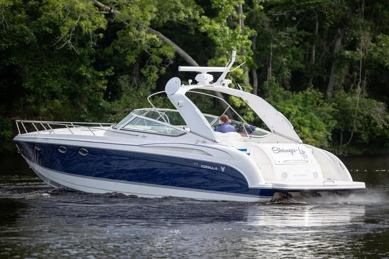 Slide: The Image of 2003 Formula 400 Super Sport boat cruising on a river with lush green trees. - 5
