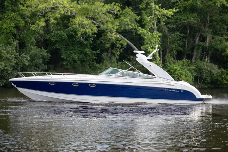Slide: The Image of 2003 Formula 400 Super Sport boat cruising on a serene lake with lush green trees. - 6