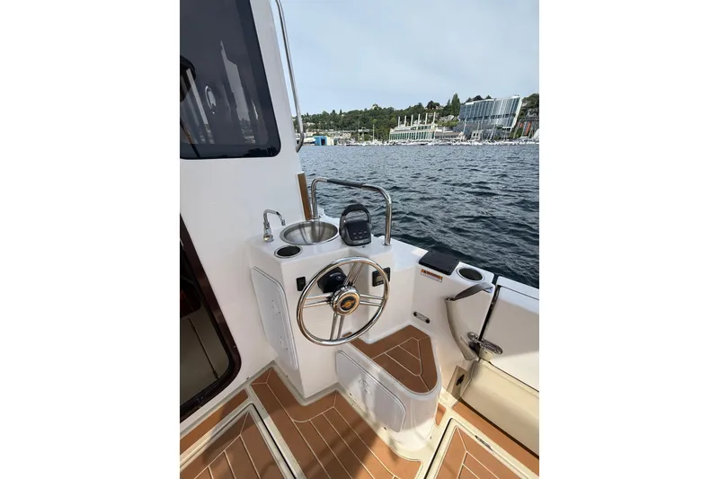 Slide: The Image of Cockpit view of 2020 Ranger Tugs R-31 CB boat with steering wheel and water backdrop. - 10