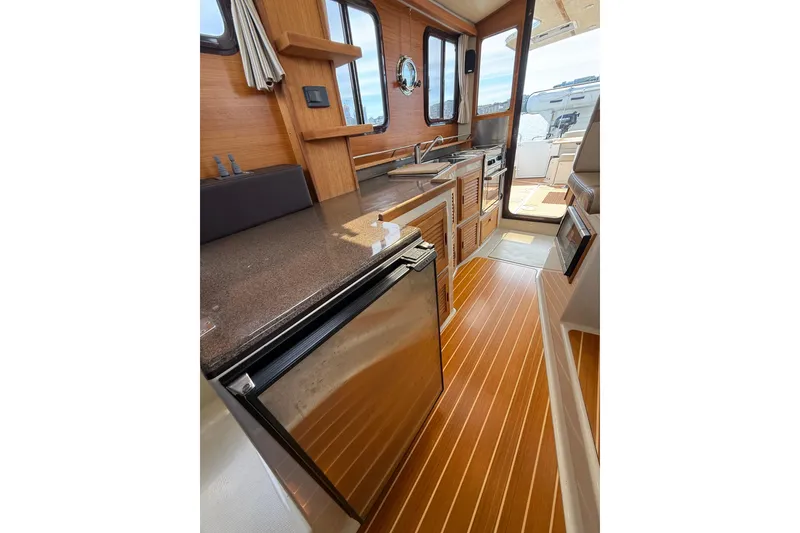 Slide: The Image of Interior of 2020 Ranger Tugs R-31 CB, featuring a modern kitchen with wood accents. - 21