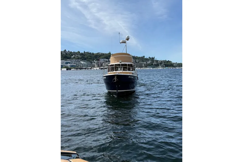 Slide: The Image of 2020 Ranger Tugs R-31 CB boat on a scenic lake with a city backdrop. - 3