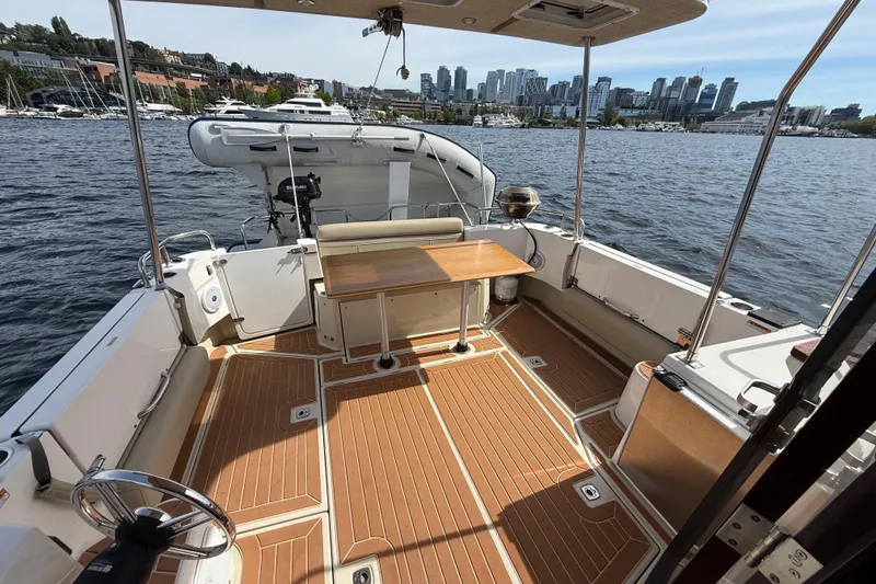 Slide: The Image of 2020 Ranger Tugs R-31 CB boat deck with table, overlooking city skyline and marina. - 5