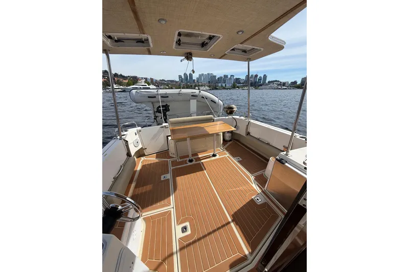 Slide: The Image of 2020 Ranger Tugs R-31 CB boat interior with wooden deck, docked by city skyline. - 6