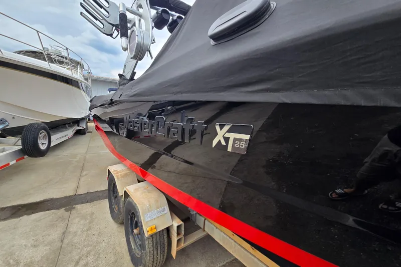 Slide: The Image of 2019 MasterCraft XT25 boat on trailer, covered and parked beside another vessel. - 10