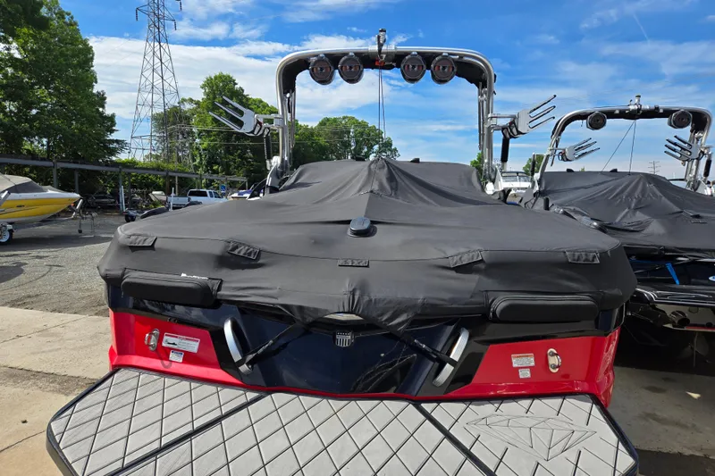 Slide: The Image of 2019 MasterCraft XT25 boat with cover, parked outdoors under a clear blue sky. - 19