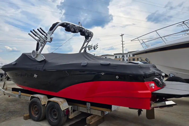 Slide: The Image of 2019 MasterCraft XT25 boat with cover on trailer, black and red design. - 2