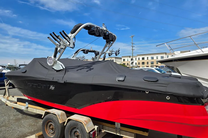 Slide: The Image of 2019 MasterCraft XT25 boat with black cover and red hull on a trailer. - 20